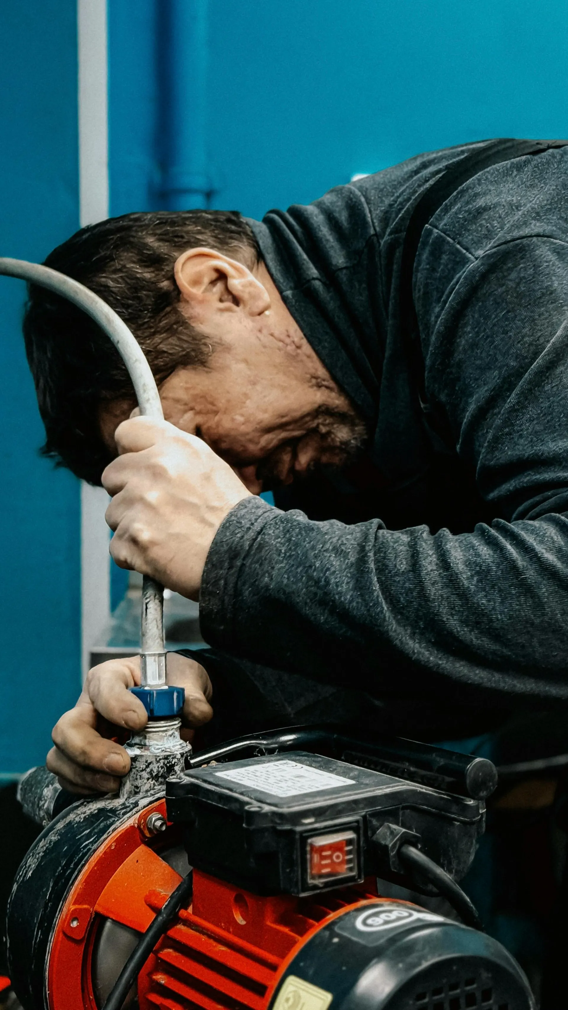Tradesman concentrating on a pump fitting on a workshop bench